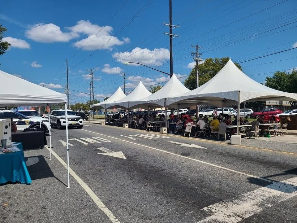 Row of white high-peak frame tents along a street for a community block party